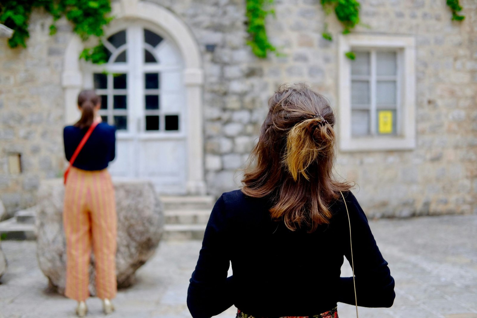 selective focus photography of woman standing in front on buidling